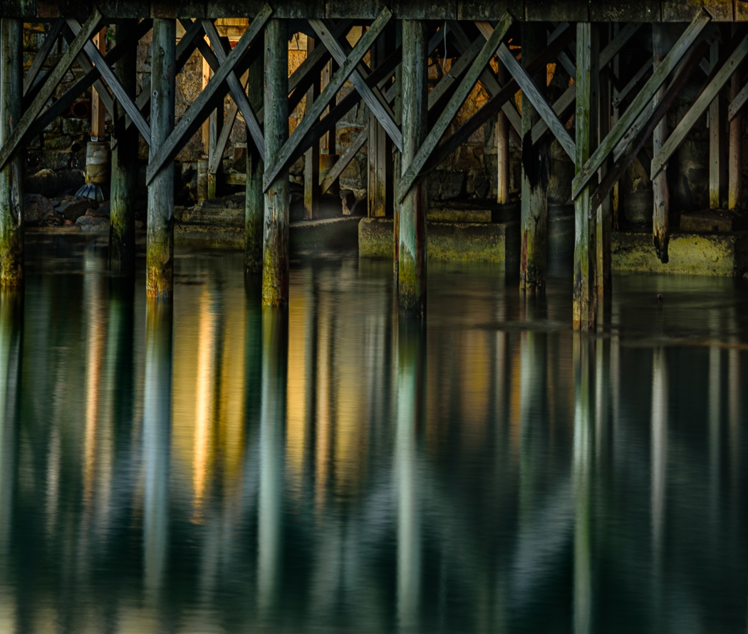 Reflection and early morning light on the pylons and water by Richard Provost